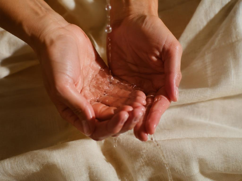 Water dripping onto hands over linen
